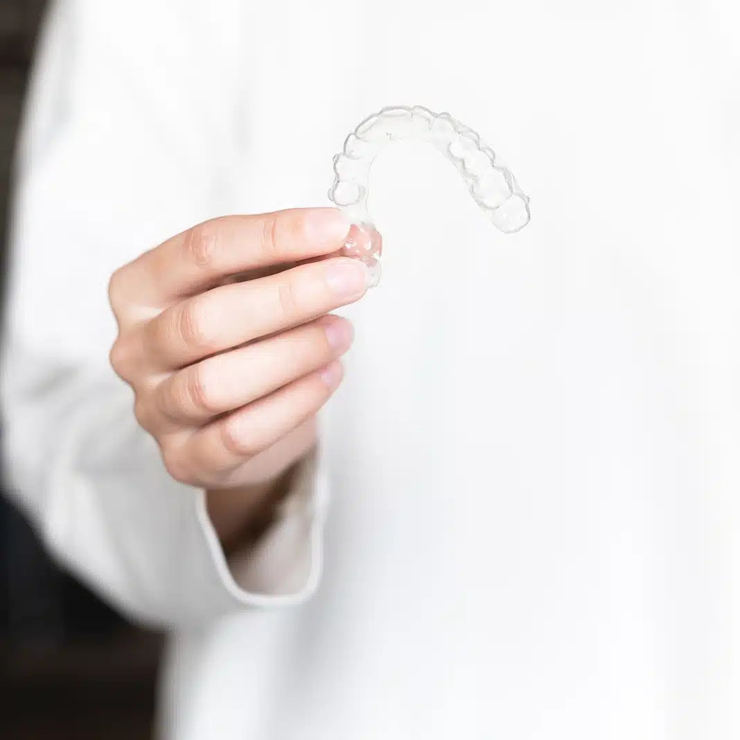 woman-holding-invisalign-aligner-queens-ny Woman holding Invisalign aligner near Queens NY House of Orthodontia